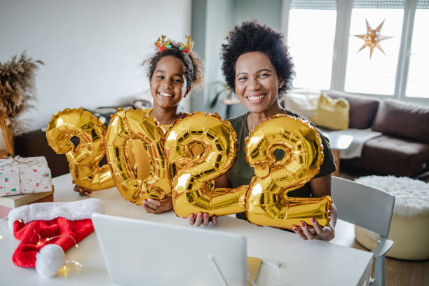 Mother and daughter holding balloons in the shape of numbers 2022. Mother and daughter are at home, they are holding 2022. balloon numbers new years day stock pictures, royalty-free photos & images