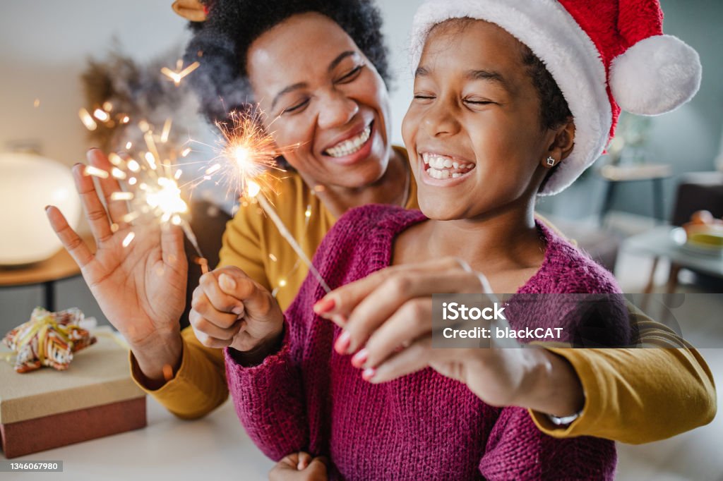 Portrait of a mother and daughter holding New Year's sparklers at home A mother and her daughter are at home, they are enjoying in Christmas holidays and holding New Year's sparklers Christmas Stock Photo