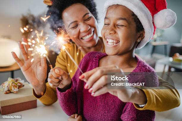 Portrait Of A Mother And Daughter Holding New Years Sparklers At Home Stock Photo - Download Image Now