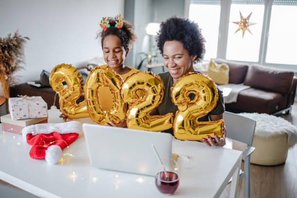 mãe e filha comemorando online 2022. ano e segurando balões - new years day new years eve new year ethnic - fotografias e filmes do acervo