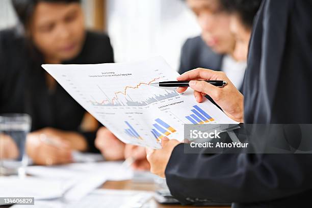 Businesspeople Reviewing Documents And Graphs Stock Photo - Download Image Now - Chart, Finance, Asian and Indian Ethnicities