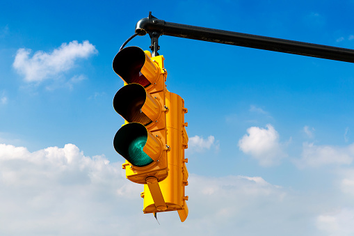 Yellow Traffic light on green against clear blue sky in New York City, NY, USA