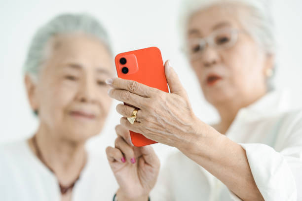 femmes âgées qui conduisent un smartphone ensemble - japan serious family senior adult photos et images de collection