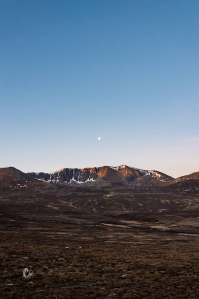 Cairngorm Snow Mountain Range at Dawn with Moon and wilderness foreground stock photo