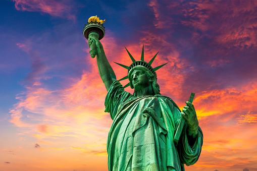 Statue of Liberty against sunset sky with beautiful cloud background in New York City, NY, USA