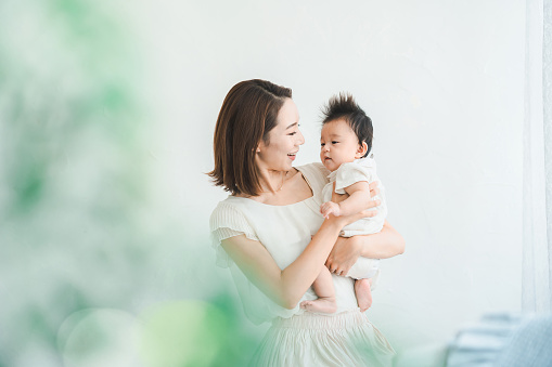 Asian mom holding a baby in the bright room