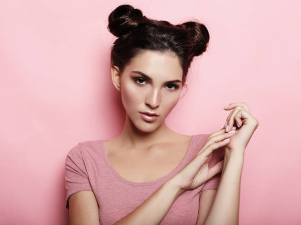 brunette girl with hairbuns wearing casual clothes poses at studio funny brunette girl with hairbuns wearing casual clothes poses at studio hair bun stock pictures, royalty-free photos & images