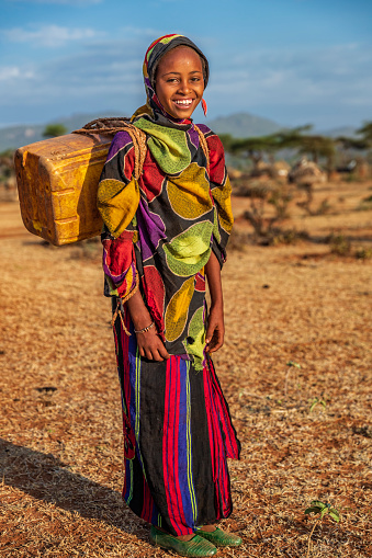 Young African women from Borana tribe carrying water to the village, African women and children often walk long distances to bring back jugs of water that they carry on their back. The Borana Oromo are a pastoralist tribe living in southern Ethiopia and northern Kenya.