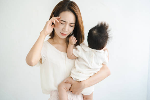 赤ちゃんを抱いて疲れているように見える母親 - 育児ノイローゼ 日本人 ストックフォトと画像