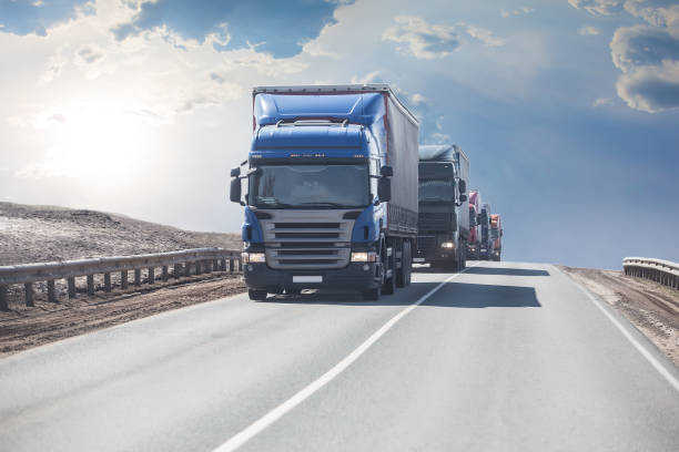 trucks driving along a highway under a cloudy sky