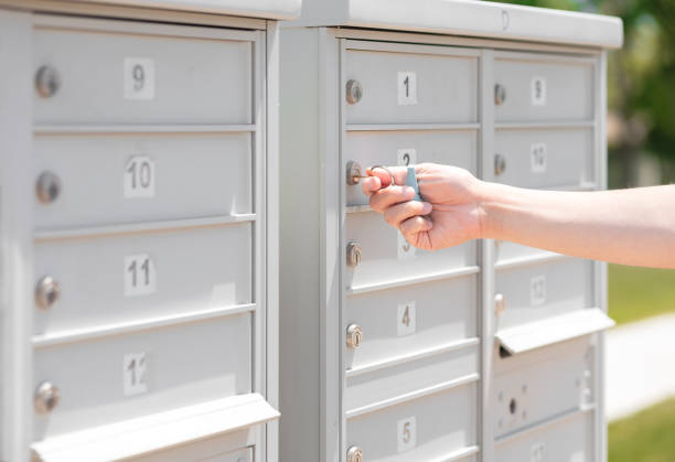 A man using key opening/locking mail box Person's hand holding key unlock-lock mailbox by house number, selective focus. Receiver gets mail and small parcel from the row of outdoor metal storage, depth of field. Man close residential letterbox. key package stock pictures, royalty-free photos & images