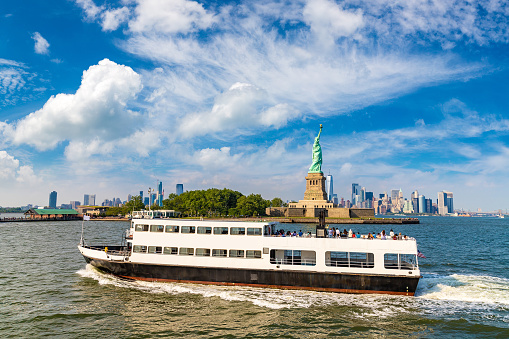 Statue of Liberty and tourist ship ferry in New York City, NY, USA