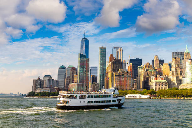 Panoramic view of Manhattan cityscape and ship ferry in New York City at sunset, NY, USA