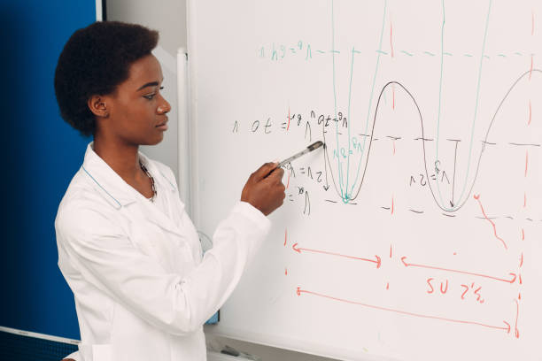 l'insegnante di matematica donna afroamericana sta alla lavagna con pennarello - professor teacher female blackboard foto e immagini stock