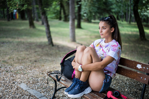 A young woman is sitting on a park bench.