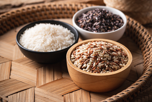 Various Organic Thai rice grain (brown, white and purple rice) in a bowl on bamboo tray