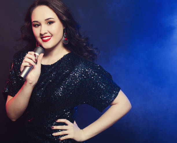istock Young happy girl singing into microphone at party 1346093895