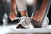 istock Cropped shot of an unrecognizable woman tying her shoelaces while exercising at the gym 1346094881