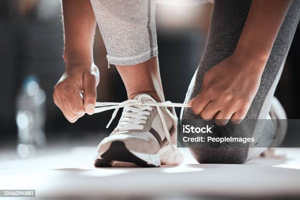 Cropped Shot Of An Unrecognizable Woman Tying Her Shoelaces While Exercising At The Gym Stock Photo - Download Image Now