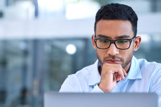 istock Shot of a young businessman using his laptop at work 1346100939