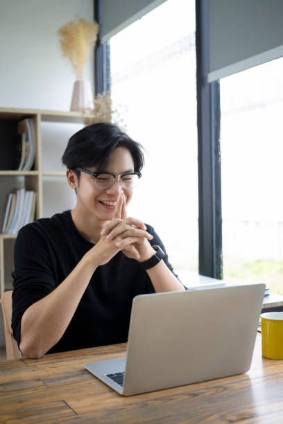 istock Smiling asian man having video conference with laptop computer. 1346106562