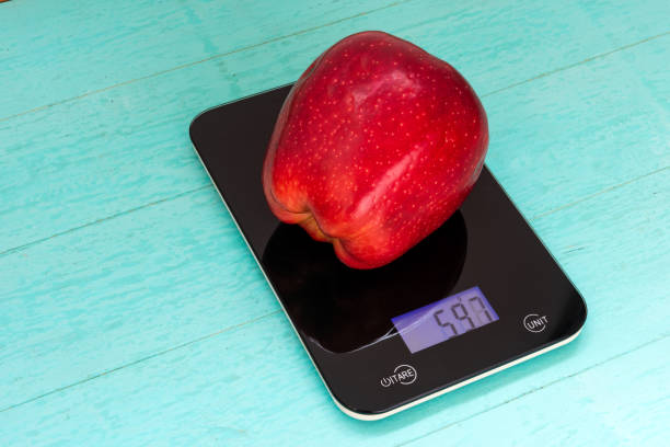 gran manzana roja en la balanza - weight scale apple comparison balance fotografías e imágenes de stock