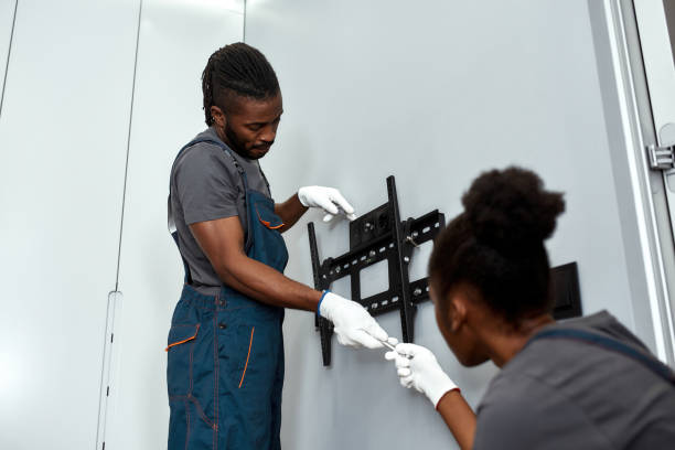 Mount service workman taking tool from female apprentice Low angle skilled mixed-race mount service worker in gloves taking tool from female apprentice, sitting on floor. Flat screen TV full motion bracket installation. Authenticity in business concept. installing tv stock pictures, royalty-free photos & images