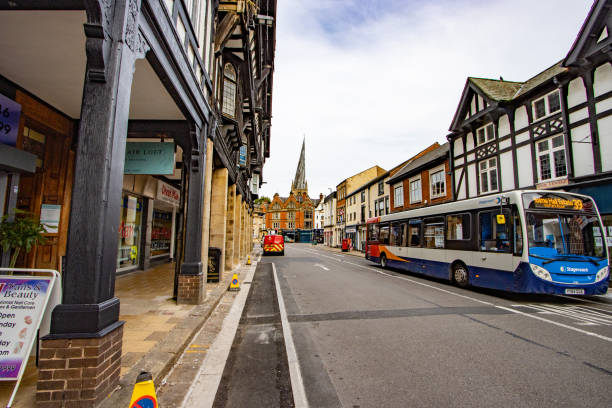 Knifesmithgate in Chesterfield, England, with a Stagecoach on the right and people and stores visible. In the background is the Crooked Spire of St Mary and All Saints Church.