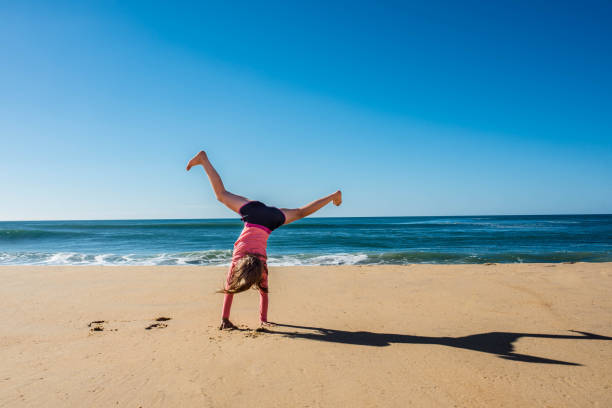 Man in bathing suit does cartwheel on reflective beach