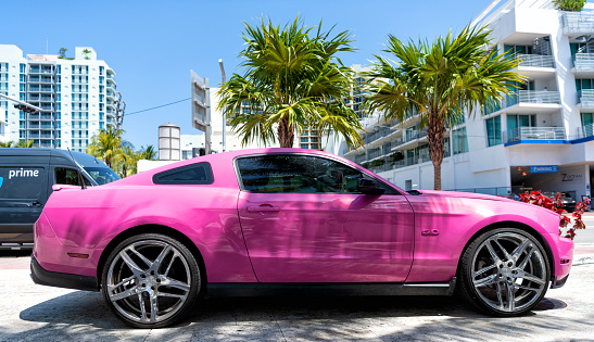 Los Angeles, California USA - April 14, 2021: ford mustang GT luxury pink car parked near palm tree. side view.