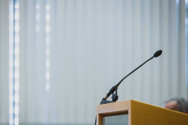 istock Single lecture microphone on a lecture stand at a conference hall. 1346118844