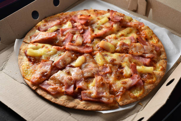 istock Pineapple and ham pizza in a cardboard box full. 1346119702