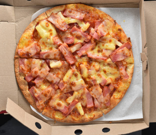 istock Pineapple and ham pizza in a cardboard box full. 1346119710