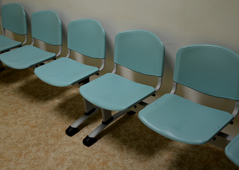 cheap plastic chairs in a row by the wall. classic waiting room at the train station or at the doctor's. corridor with washable surface for better hygiene