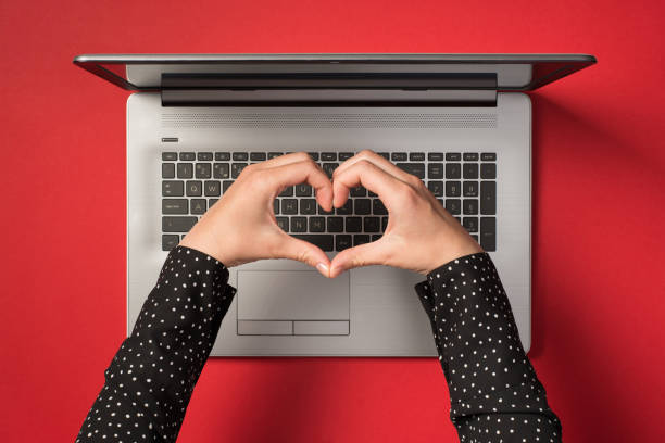 Overhead photo of grey laptop and hands with gesture as heart isolated on the red backdrop Overhead photo of grey laptop and hands with gesture as heart isolated on the red backdrop Love stock pictures, royalty-free photos & images