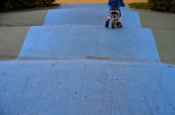 Photo of Skateboard, skating park for roller skating with a concrete cement surface painted blue and yellow. turns and training waves with obstacles. Freestyle cycling, children Protective clothing