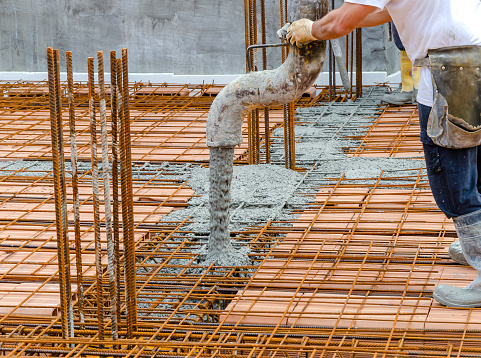 Trabajador de la construcción vertiendo concreto en el marco de barras de refuerzo de acero photo