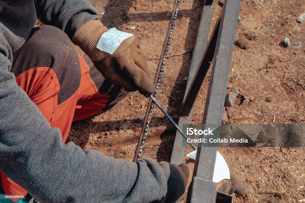 Closeup of lumberjack sharpening a chainsaw with file Sharpening Stock Photo