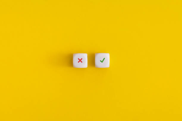 istock Cross and check mark on a white cubes on yellow background. Approving, voting or right decision concept. 1346121240
