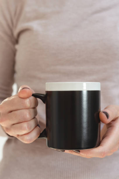 istock Black coffee mug mockup for design demonstration. Stylish cup mock up in female hands. 1346122105
