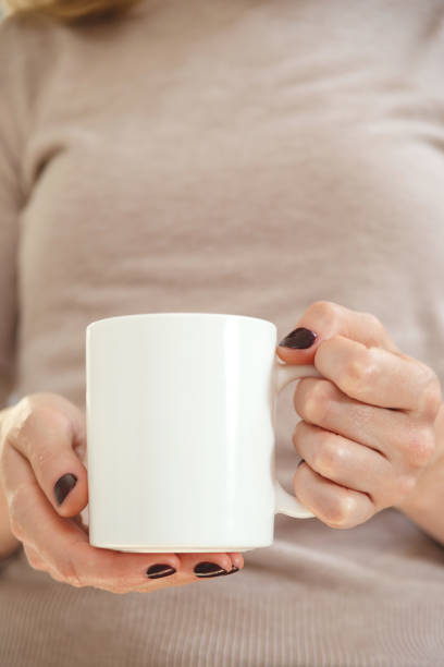 istock White coffee mug mockup for design demonstration. Stylish cup mock up in female hand. 1346122111