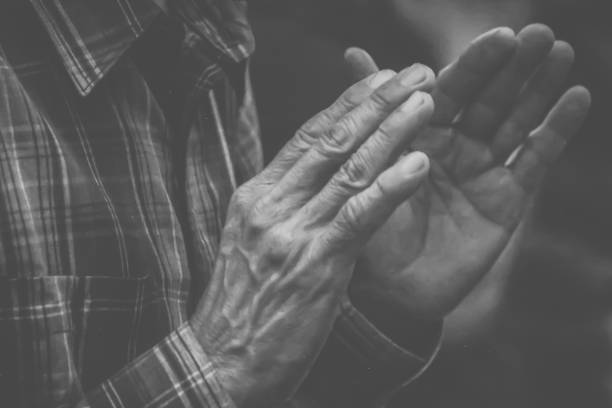 Close-up of a senior man's hand holding his breakfast coffee cup mug using his thumb and index finger.