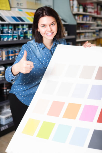 istock smiling female customer examining color scheme variants in paint store 1346123889