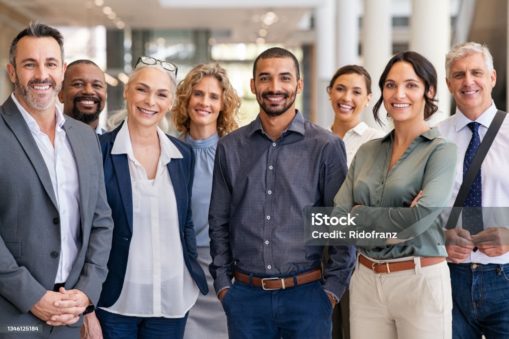 Group of successful multiethnic business team Portrait of successful group of business people at modern office looking at camera. Portrait of happy businessmen and satisfied businesswomen standing as a team. Multiethnic group of people smiling and looking at camera. Teamwork Stock Photo
