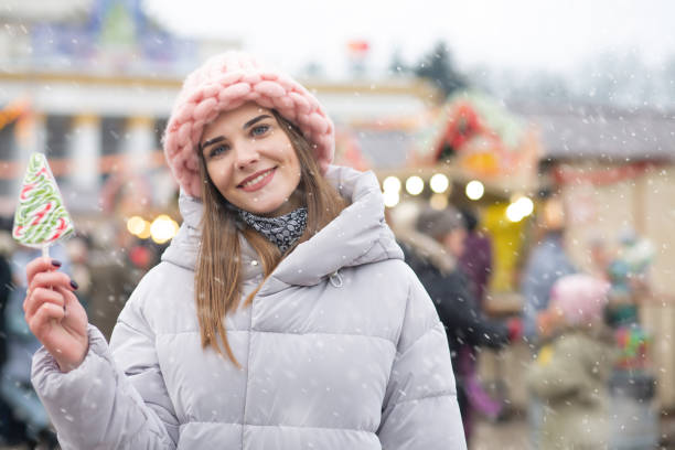 istock Stunning lady with candy on a christmas fair during the snowfall 1346125607