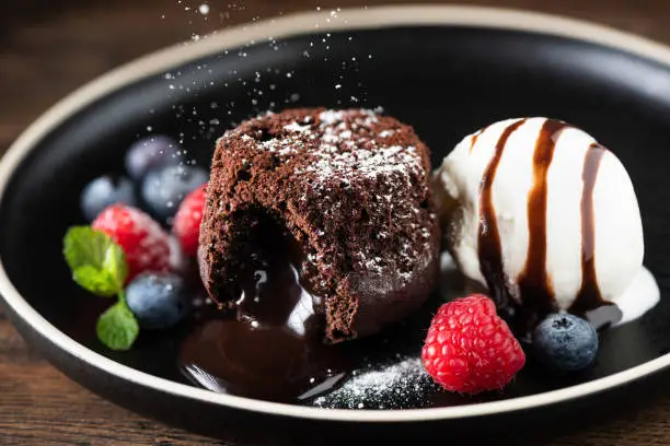 Chocolate fondant cake, molten lava cake with ice cream scoop and fresh berries on plate