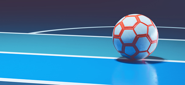 White orange futsal ball on blue indoor soccer field concept background