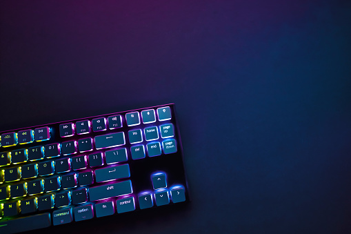 Cropped view of backlighted gaming computer keyboard from above. Professional computer game playing, esport business and online world concept.
