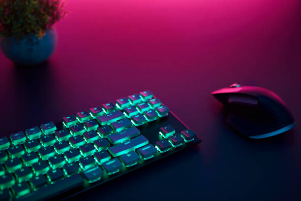 istock High angle view of backlighted keyboard and mouse laying on desk. Purple light from top. 1346129651