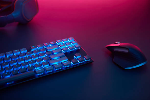 istock High angle view of backlighted keyboard and mouse laying on desk. Purple light from top. 1346129812